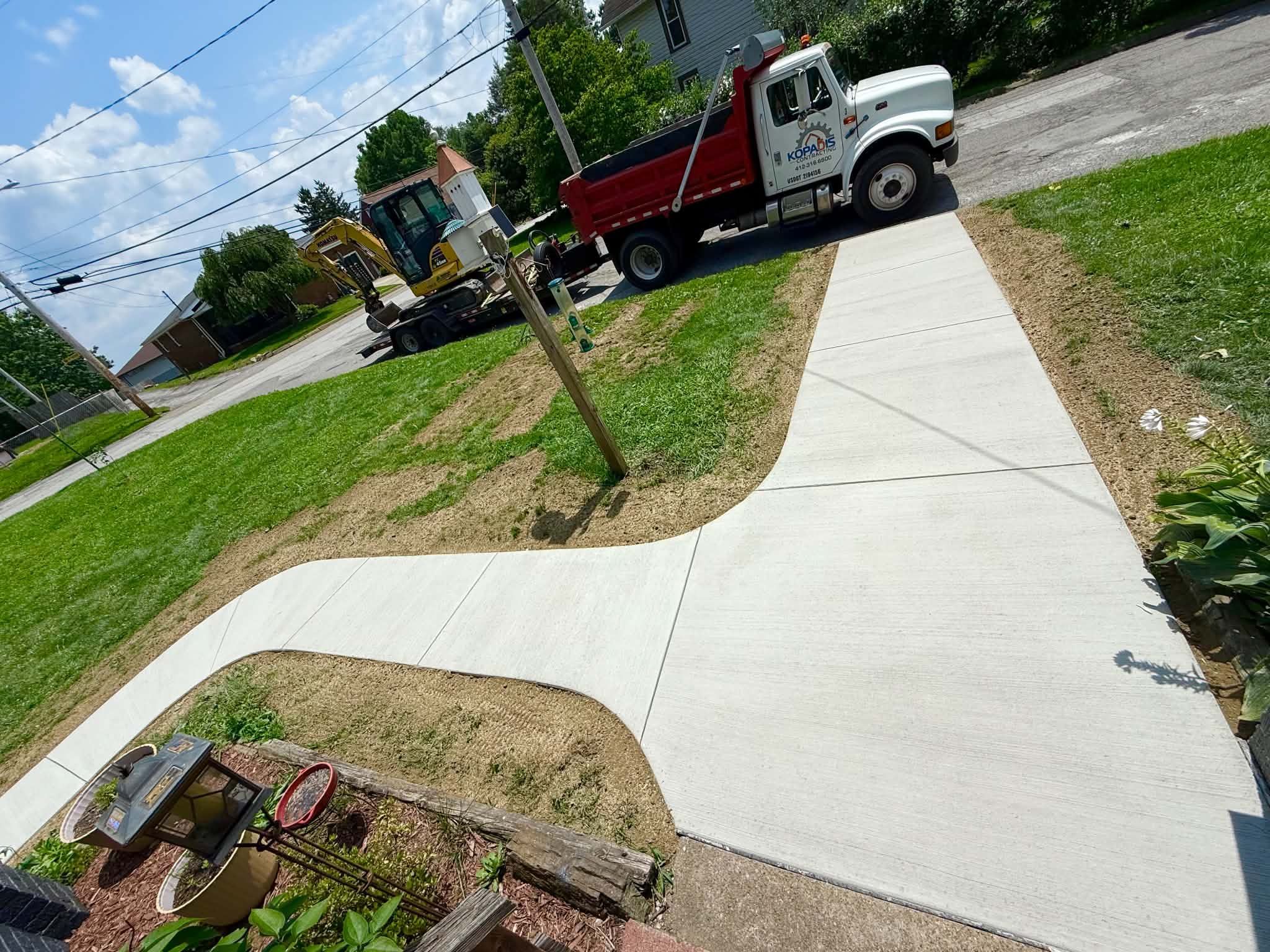 New concrete sidewalk with a curved branch leading toward a house.